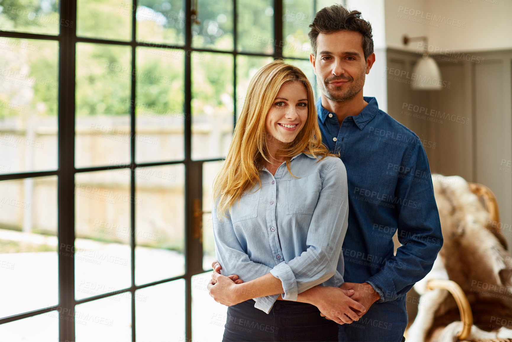 Buy stock photo Support, portrait or couple in house with hug, connection or bonding together on weekend break. Security, love or people in lounge with embrace, partner trust or happy moment in romantic relationship