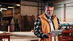 Man, tablet and scroll in carpentry workshop, check lumber order or online inventory management. Mature, carpenter and tech for digital stock analysis or search woodworking merchandise app for info