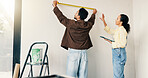 Measuring, tool and couple in new home for renovation, maintenance or property development. Tape, real estate and man with woman for precision on wall for construction repairs in apartment together.