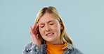 Headache, tired and woman in studio with pain, frustrated or tension with discomfort. Fatigue, space and female person on blue background with migraine pressure, burnout or sore head with dizziness. 
