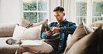 Cellphone, relax and man on sofa in home with texting, chatting or social media on mobile app. Tech, chilling and person on phone for reading online blog for tips or advice in living room at house.