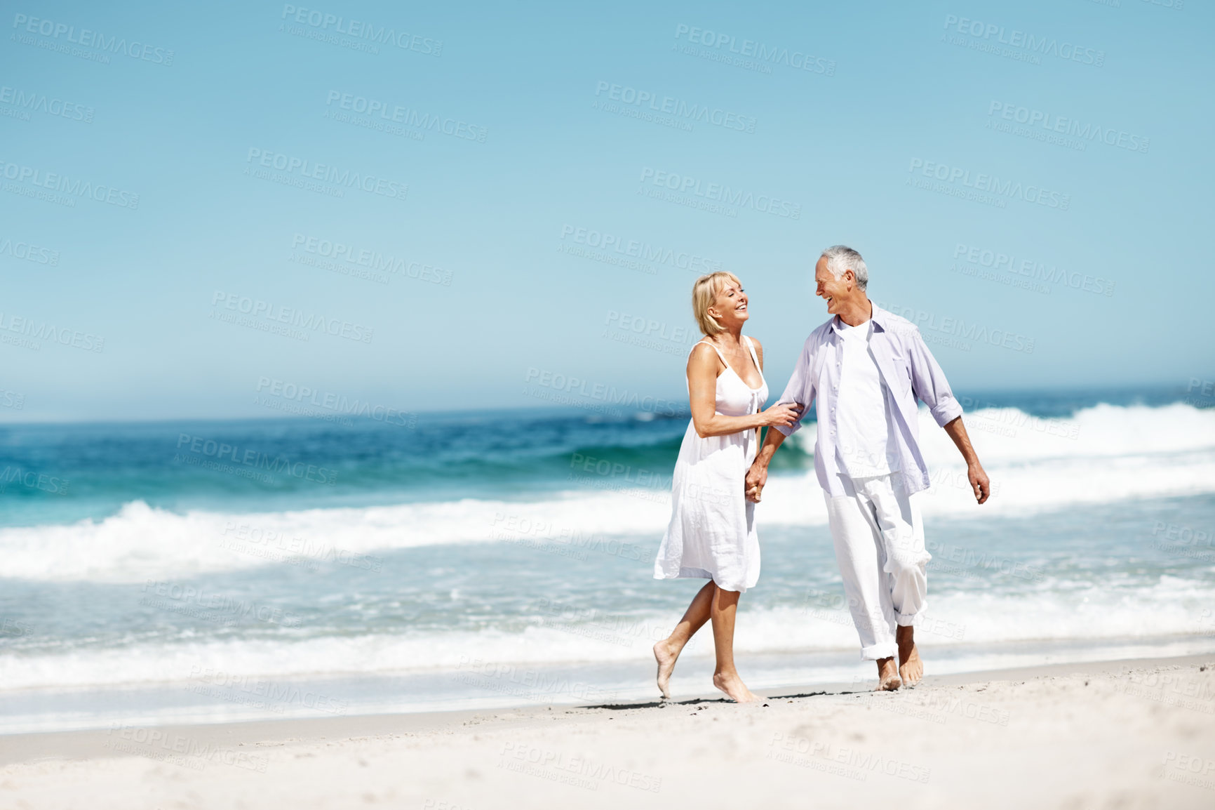 Buy stock photo Couple, smile and holding hands at beach with love, commitment or playful for anniversary. Space, happy and mature people at ocean with affection, marriage milestone or healthy relationship with care