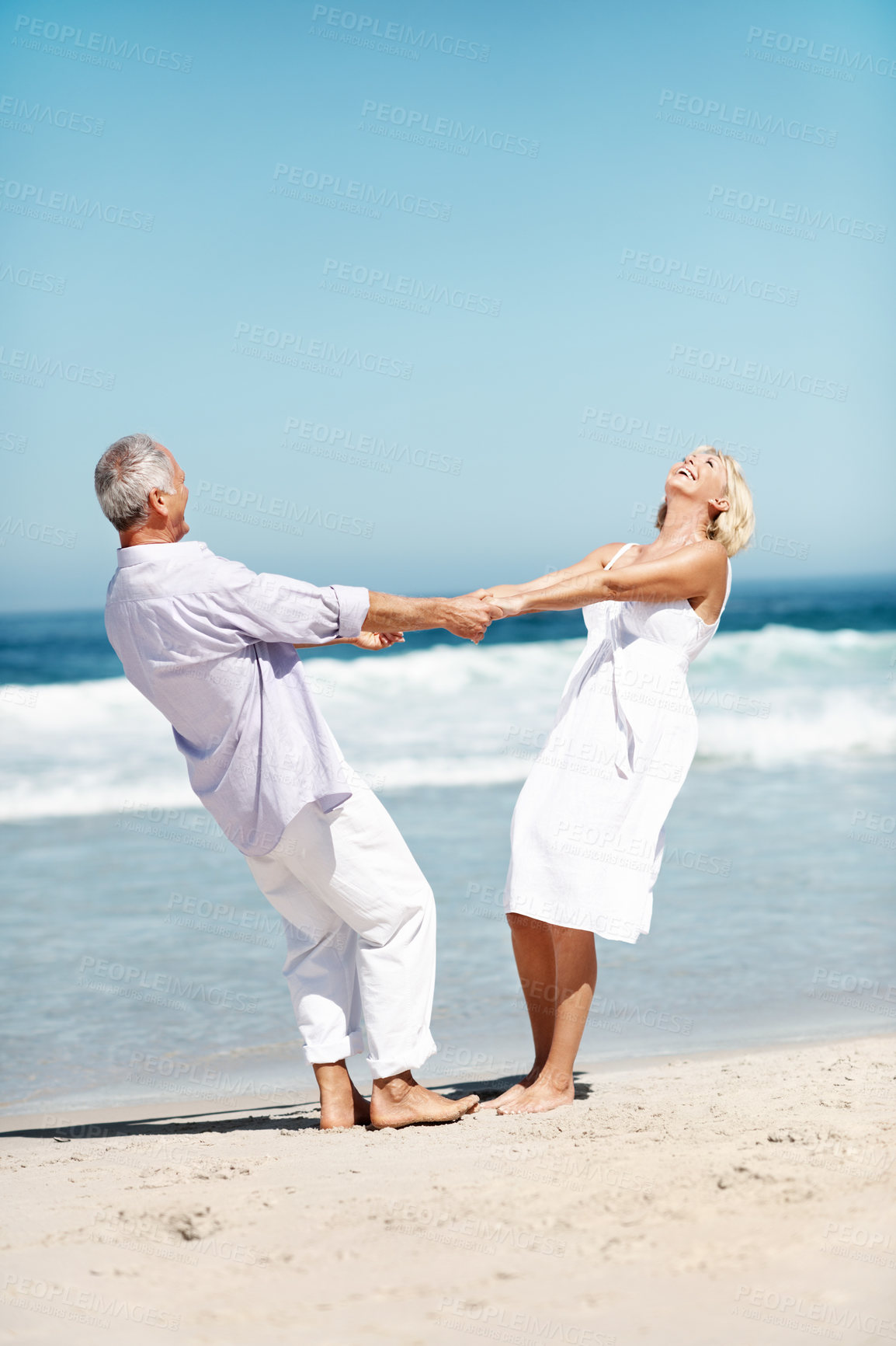 Buy stock photo Holding hands, laughing and mature couple at beach for bonding, marriage and playful relationship. Space, happy and man with woman by ocean for summer holiday, vacation and anniversary for love