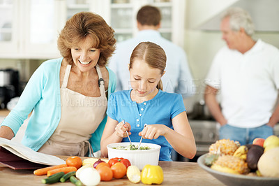 Buy stock photo Grandma, reading and cooking with child in kitchen, bonding or learning culinary skills in apartment. Happy, senior woman and meal prep with girl, family connection and teaching recipe in house