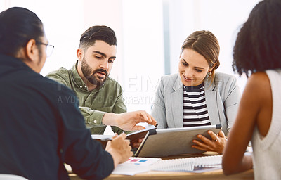 Buy stock photo Shot of young businesspeople using a digital tablet during a meeting in a modern office