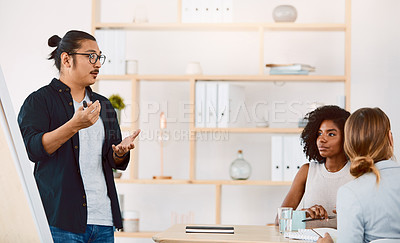 Buy stock photo Shot of a young businessman delivering a presentation to his colleagues in a modern office