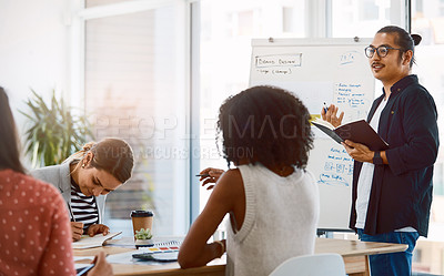 Buy stock photo Shot of a young businessman delivering a presentation to his colleagues in a modern office