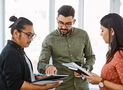 Buy stock photo Shot of young businesspeople using a digital tablet during a meeting in a modern office