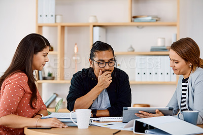 Buy stock photo Shot of young businesspeople using a digital tablet during a meeting in a modern office