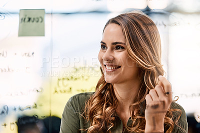 Buy stock photo Shot of an attractive young businesswoman planning and writing notes on a glass wall in her office at work