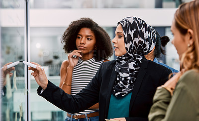Buy stock photo Shot of a group of young businesspeople planning and writing notes on a glass wall in an office at work