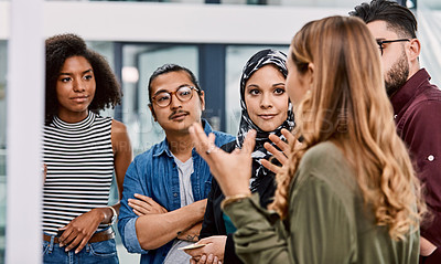 Buy stock photo Shot of a group of young businesspeople planning and writing notes on a glass wall in an office at work