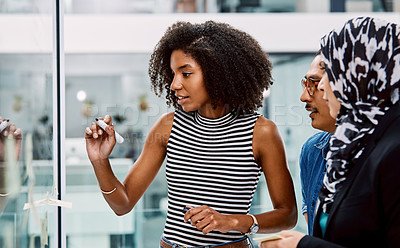 Buy stock photo Shot of a group of young businesspeople planning and writing notes on a glass wall in an office at work