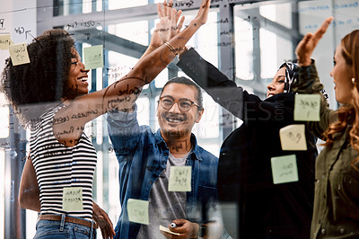 Buy stock photo Shot of a group of young businesspeople celebrating and giving each a high five in their office at work