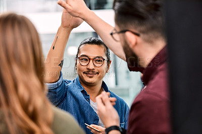 Buy stock photo Shot of a group of young businesspeople celebrating and giving each a high five in their office at work