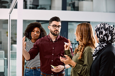 Buy stock photo Shot of a group of young businesspeople planning and writing notes on a glass wall in an office at work