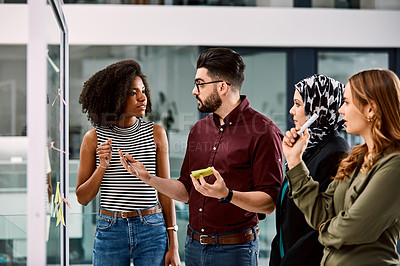 Buy stock photo Shot of a group of young businesspeople planning and writing notes on a glass wall in an office at work