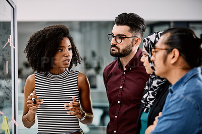 Buy stock photo Shot of a group of young businesspeople planning and writing notes on a glass wall in an office at work