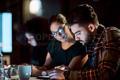 Buy stock photo Shot of a young businessman using a digital tablet during a late night meeting at work