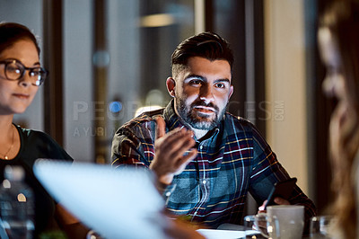 Buy stock photo Shot of a group of young businesspeople having a late night meeting at work