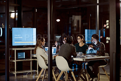 Buy stock photo Shot of a group of young businesspeople having a late night meeting at work