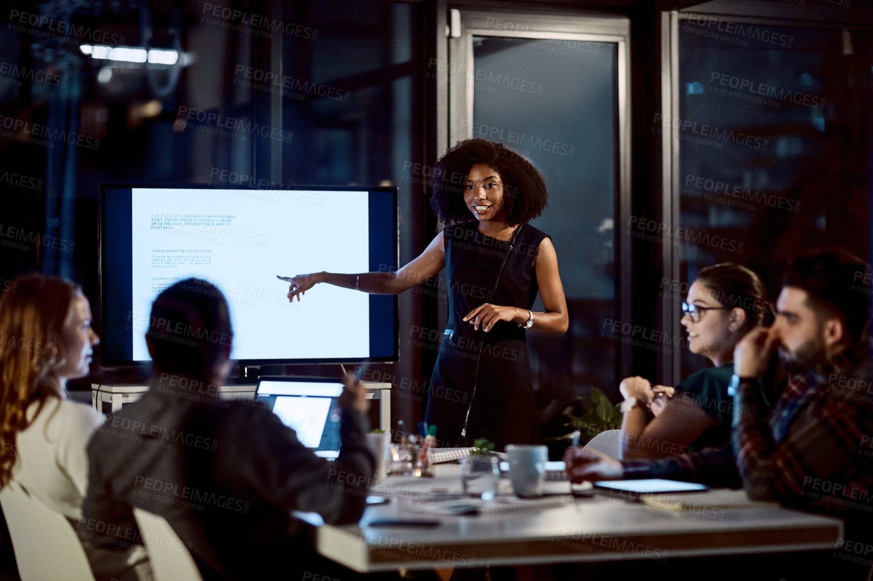 Buy stock photo Shot of a young businesswoman delivering a presentation during a late night meeting at work