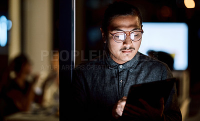 Buy stock photo Shot of a young businessman using a digital tablet during a late night at work
