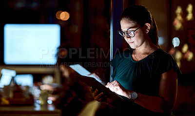 Buy stock photo Shot of a young businesswoman using a digital tablet during a late night at work