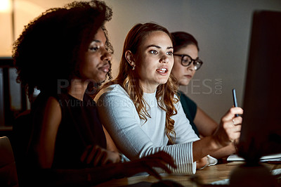 Buy stock photo Shot of a group of young businesswomen using a computer during a late night at work