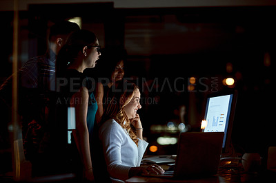 Buy stock photo Shot of a group of young businesspeople using a computer during a late night at work
