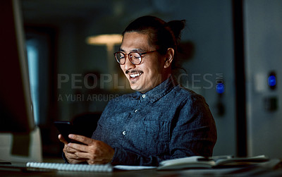Buy stock photo Shot of a young businessman using a smartphone during a late night at work