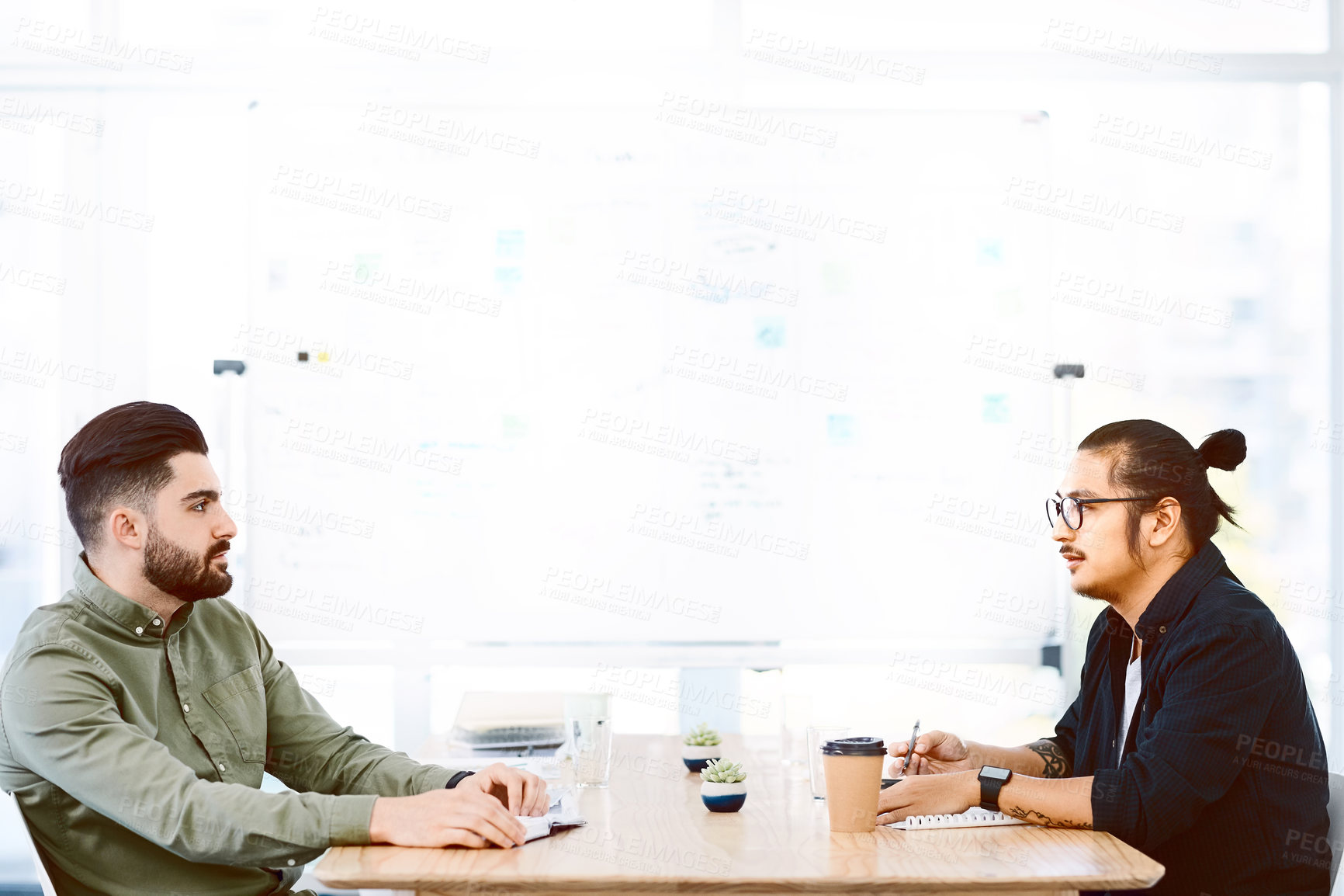 Buy stock photo Shot of two young businessmen having a meeting in a modern office