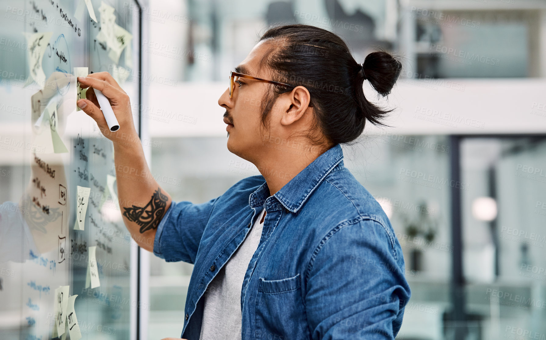 Buy stock photo Shot of a handsome young businessman planning and writing notes on a glass wall in his office