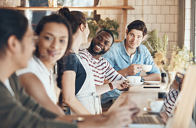 Buy stock photo Shot of a friendly young waitress serving coffee to young business partners in a coffee shop during the day