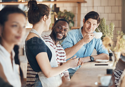 Buy stock photo Shot of a friendly young waitress serving coffee to young business partners in a coffee shop during the day
