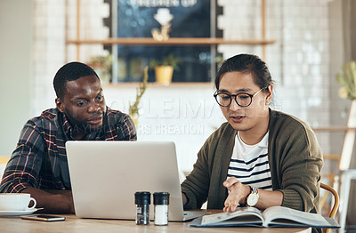 Buy stock photo Shot of handsome young businessmen sitting and working on a laptop in a coffee shop during the day