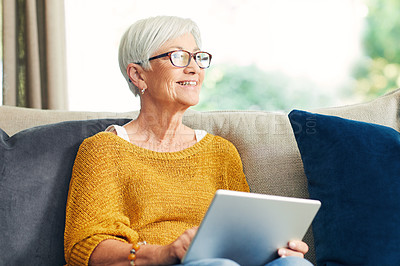 Buy stock photo Shot of a senior woman using a digital tablet on the sofa at home