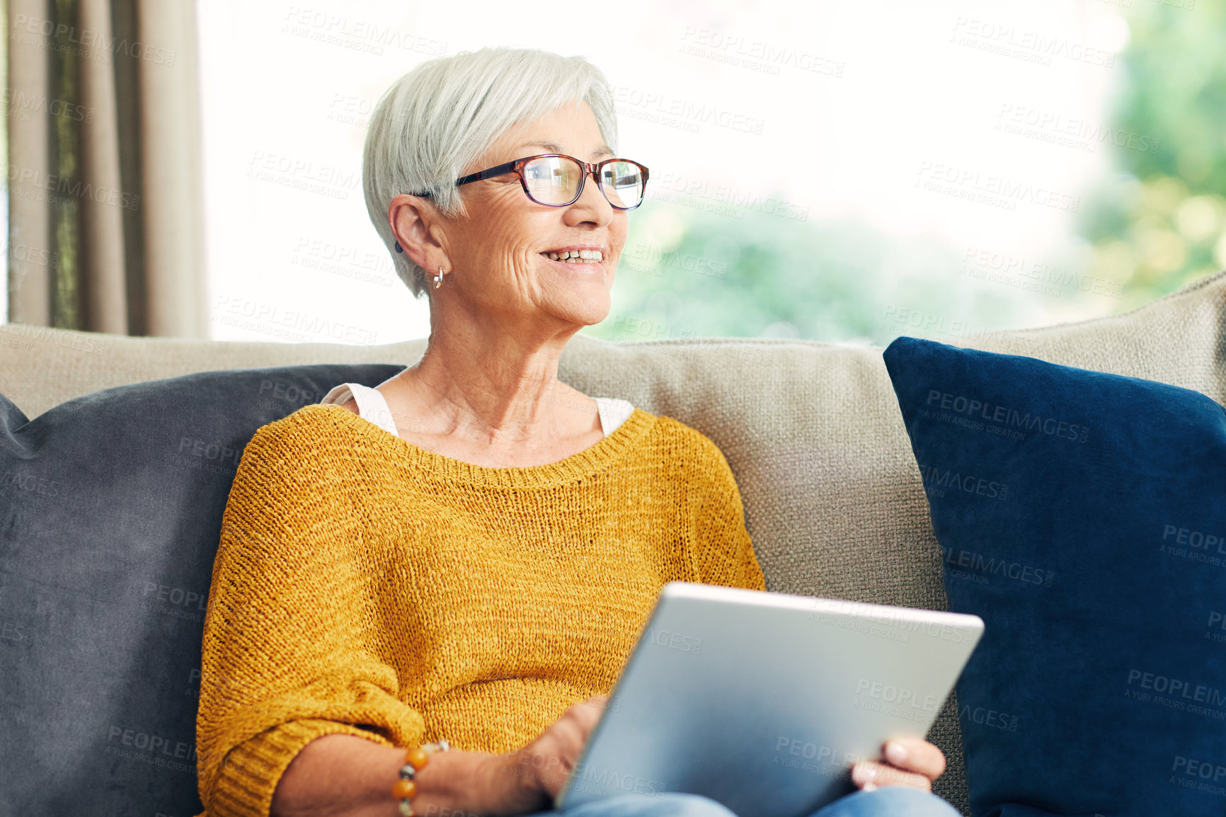 Buy stock photo Shot of a senior woman using a digital tablet on the sofa at home