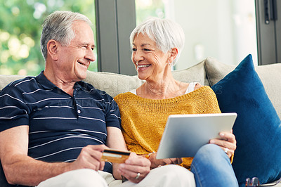 Buy stock photo Shot of a senior couple using a credit card and digital tablet on the sofa at home