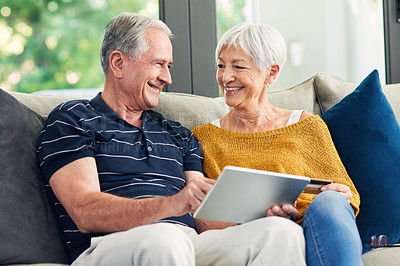Buy stock photo Shot of a senior couple using a credit card and digital tablet on the sofa at home