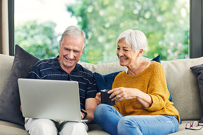 Buy stock photo Shot of a senior couple using a laptop on the sofa at home