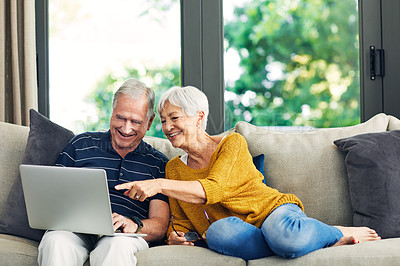 Buy stock photo Shot of a senior couple using a laptop on the sofa at home
