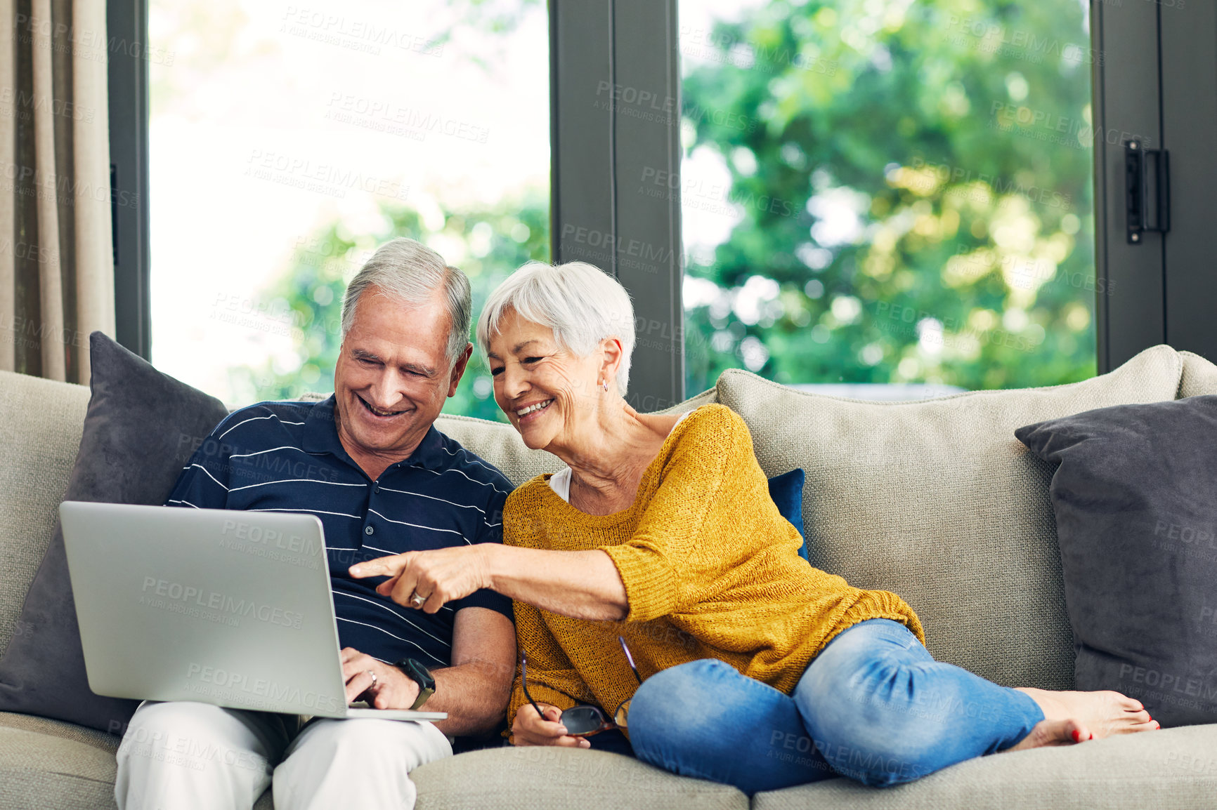 Buy stock photo Shot of a senior couple using a laptop on the sofa at home