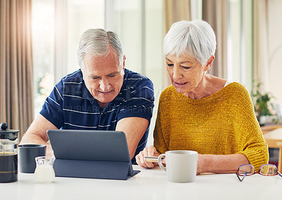 Buy stock photo Shot of a senior couple using a digital tablet and having coffee at home