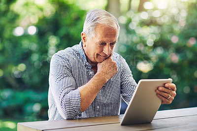Buy stock photo Shot of a senior man using a digital tablet in his backyard
