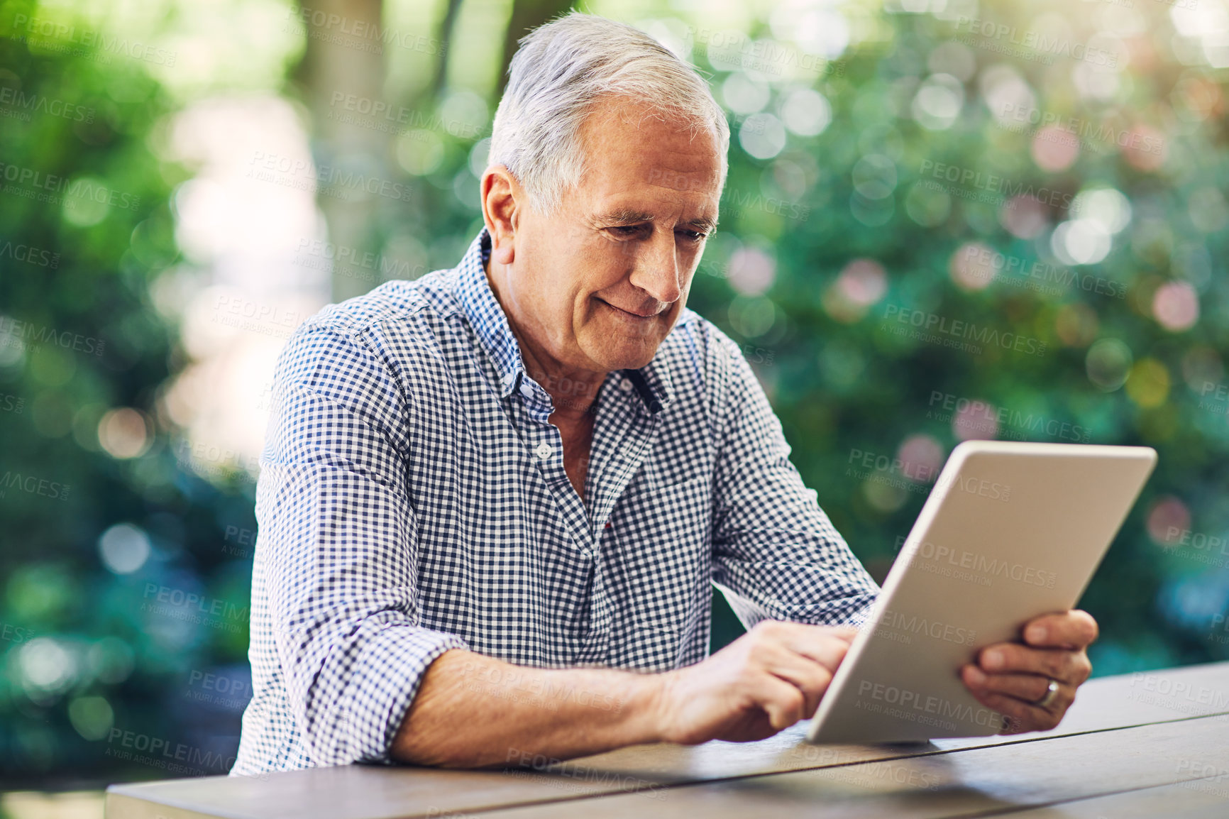 Buy stock photo Shot of a senior man using a digital tablet in his backyard