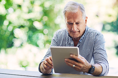 Buy stock photo Shot of a senior man using a digital tablet in his backyard