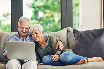 Buy stock photo Shot of a senior couple using a laptop on the sofa at home