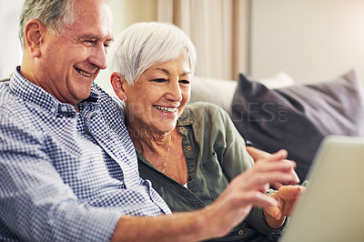Buy stock photo Shot of a waving senior couple using a laptop on the sofa at home