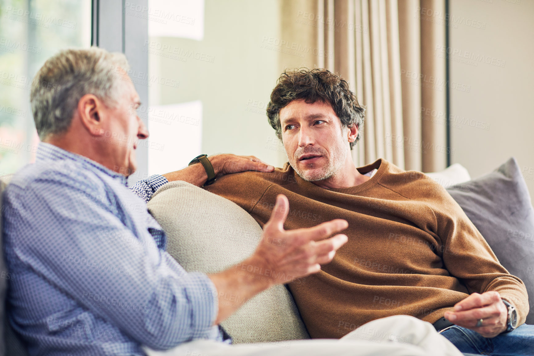 Buy stock photo Shot of a mature man and his elderly father sitting on the sofa at home and chatting